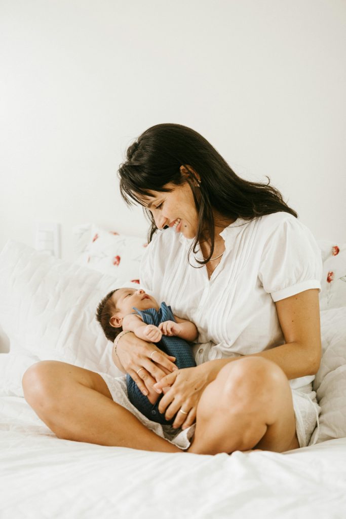 zipwp-image-3763585 A mother lovingly cradles her baby in a serene bedroom setting.